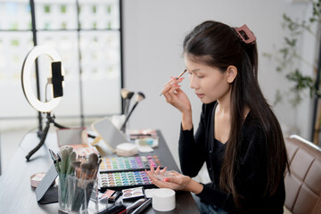 Asia woman beauty influencer makeup artist vlogger live streaming makeup tutorial on smartphone for social media
