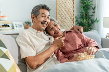 Asian senior elderly couple watching television in living room at home.