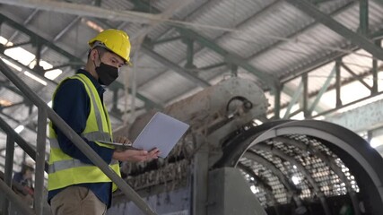 An Engineer working on a laptop surrounded by industrial recycling machines, analyzing data and optimizing processes in waste separation plant. - Powered by Adobe
