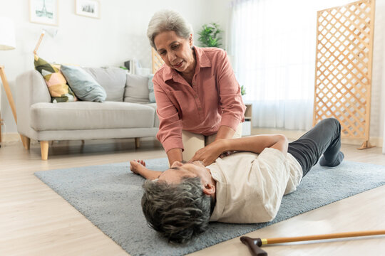 Asian senior wife helping elderly husband from falling on the ground. 