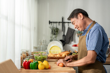 Asian senior elderly man cooking foods for breakfast in kitchen at home.