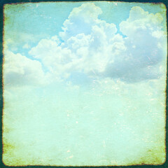Retro background with texture of old soiled paper of blue color and white clouds. Vintage square nature backdrop with grunge frame. Copy space for text