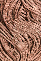 Close-up of strands of light brown cord across the entire screen. Background made of tangled threads. Macro. Top view.
