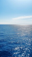 Blue ocean under clear sky with sunlight reflections