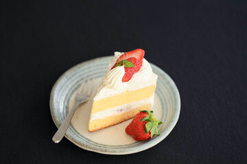 Japanese shortcake with strawberries on top is placed on a black cloth