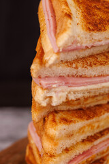 Gourmet Ham and Cheese Sandwiches Forming a Vertical Tower on a Dark Surface