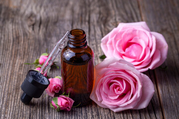 Bottles of essential rose oil and flowers