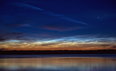 Lake at night, sky with stars, reflection in water, noctilucent clouds