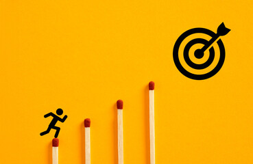 Businessman running on matches towards target on yellow background