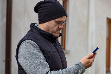 A man with a smartphone walking through an autumn city.