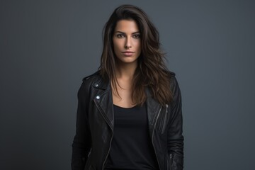 Obraz premium A woman in a black leather jacket stands in front of a gray background