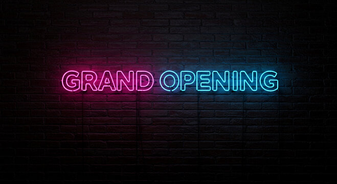 Vibrant neon sign spelling 'Grand Opening' shines brightly on a dark brick wall, perfect for announcements of new business launches or special event promotions.