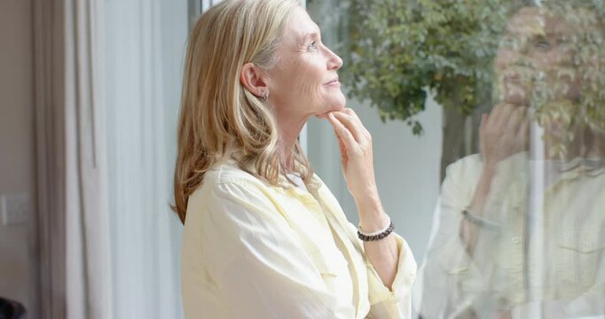 Looking out window, senior woman enjoying peaceful moment at home