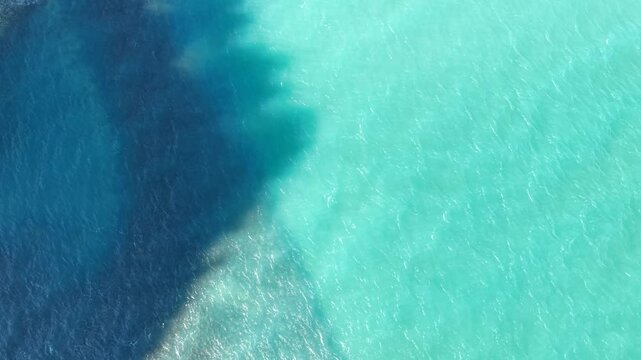 Beautiful surface of the sea water, one half of the water illuminated by the sun, the other half of the water in the shadow of a rock 
