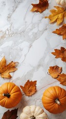 A festive autumn arrangement with pumpkins and colorful leaves on a marble surface.