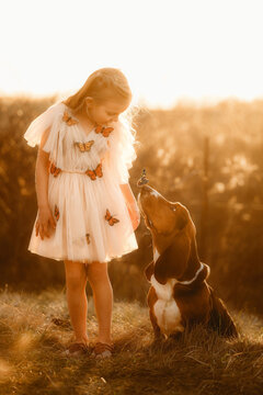little girl wearing a butterfly dress with her basset hound