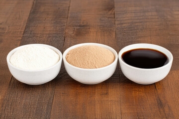 Three bowls of different ingredients are arranged on a wooden table