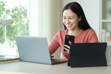 Happy asian woman using several devices at home