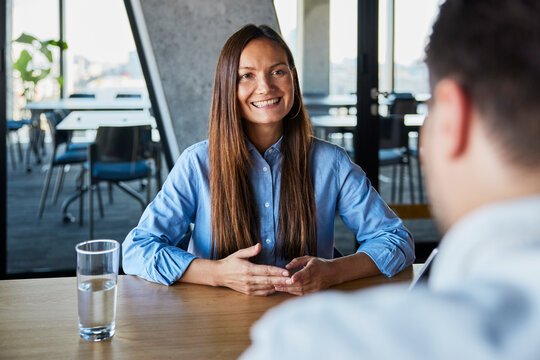 Happy manager discussing performance review with colleague at desk