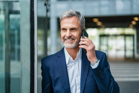 Smiling gray haired businessman talking on smart phone