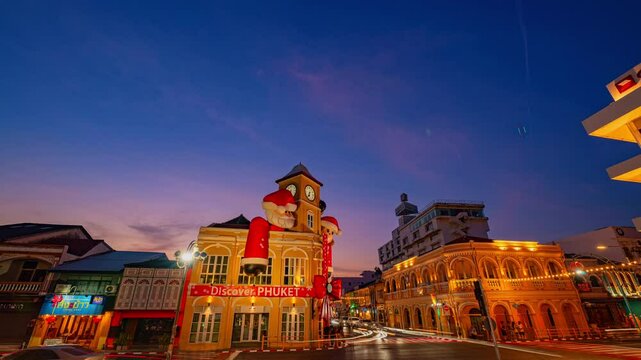 Phuket,Thailand-December,30,2024: A vibrant scene featuring a historic yellow clock tower adorned with giant Santa Claus and Mrs. Claus decorations during a dramatic evening sky. Happy New Year 2025