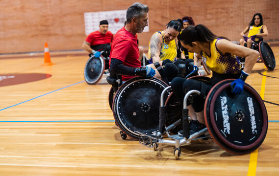 Disabled athletes sitting in wheelchair and playing rugby at sports center