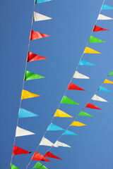 garland with colorful flags in front of blue sky, festival decoration