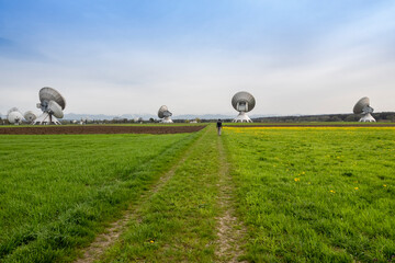 Man walking in field near satellite dishes under sky
