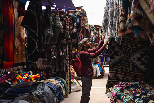 Smiling tourist selecting shawls at market