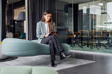 Business woman sitting on sofa with tablet PC at office