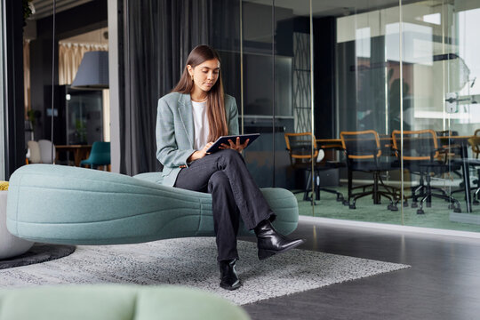 Business woman sitting on sofa with tablet PC at office