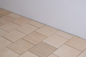 Fototapeta premium Base for floor coverings, parquet or laminate. Laying of the rough floor, a substrate of thick plywood in the form of squares with technological gaps. Repair work. Apartment renovation, building