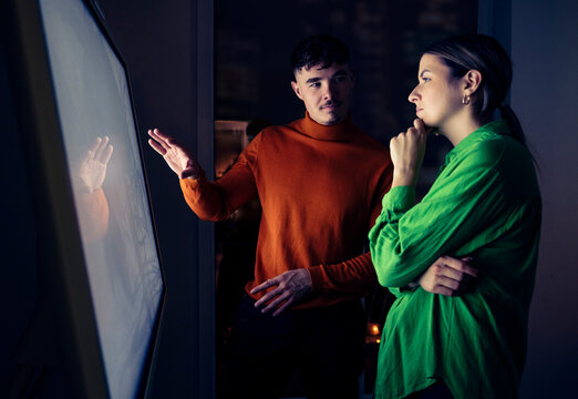Man explaining woman near digital screen in office