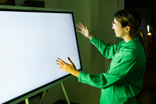 Woman wearing smart glasses standing in front of digital screen at office