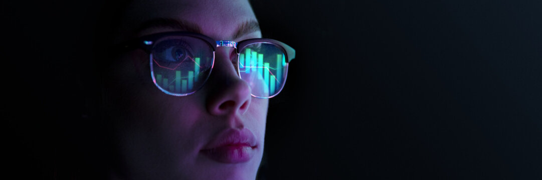Close-up of woman wearing glasses reflecting digital bar charts and graphs, symbolizing data analysis, technology, and statistics. Concept of business, modern technologies, finance. Banner - Powered by Adobe
