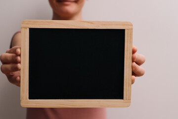 Holding Blank Blackboard. Woman showing chalkboard. Cropped image of woman holding empty black board
