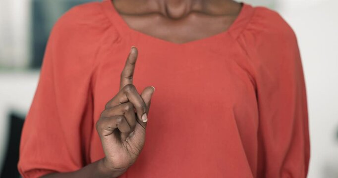 Close-up of womans hand making NO gesture by raising her index finger. Showing sign of rejection, disapproval, or warning, non-verbal expression of refusal. Feminism, social issues, message of caution