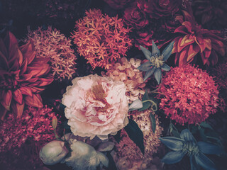 A vintage-styled image showcasing a rich arrangement of artificial flowers in deep reds and pinks,...