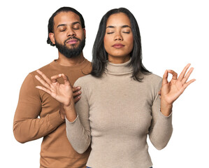 Young Latino couple in studio relaxes after hard working day, she is performing yoga.
