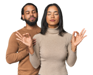 Young Latino couple in studio relaxes after hard working day, she is performing yoga.