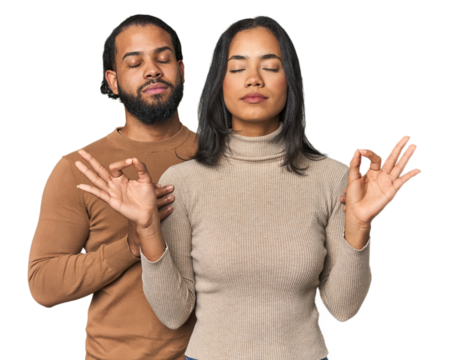 Young Latino couple in studio relaxes after hard working day, she is performing yoga. - Powered by Adobe