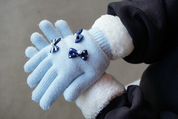 冬の寒い日に手袋をした小学生の女の子の手。可愛い水色リボン付き手袋。