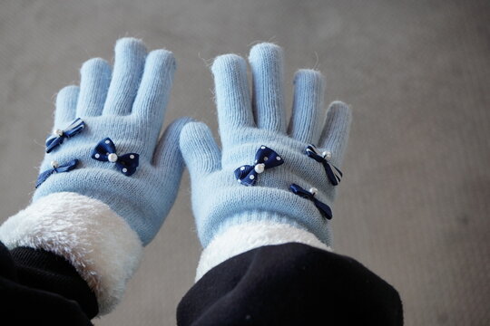 冬の寒い日に手袋をした小学生の女の子の手。可愛い水色リボン付き手袋。 - Powered by Adobe