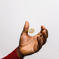 One Ghanaian cedi coin hovering suspending in palm of black African hand over white background. 1...