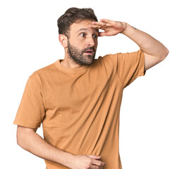 Studio portrait of young Hispanic male looking far away keeping hand on forehead.