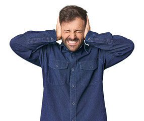 Studio portrait of young Hispanic male covering ears with hands trying not to hear too loud sound.