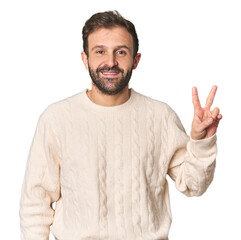 Fototapeta premium Studio portrait of young Hispanic male joyful and carefree showing a peace symbol with fingers.
