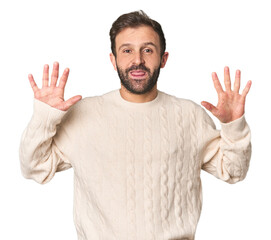 Fototapeta premium Studio portrait of young Hispanic male showing number ten with hands.