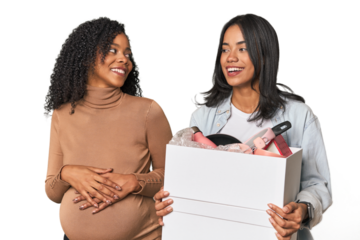 Latin women couple moving, one pregnant  looks aside smiling, cheerful and pleasant.
