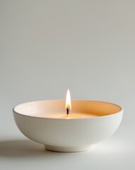 there is a candle that is lit in a white bowl